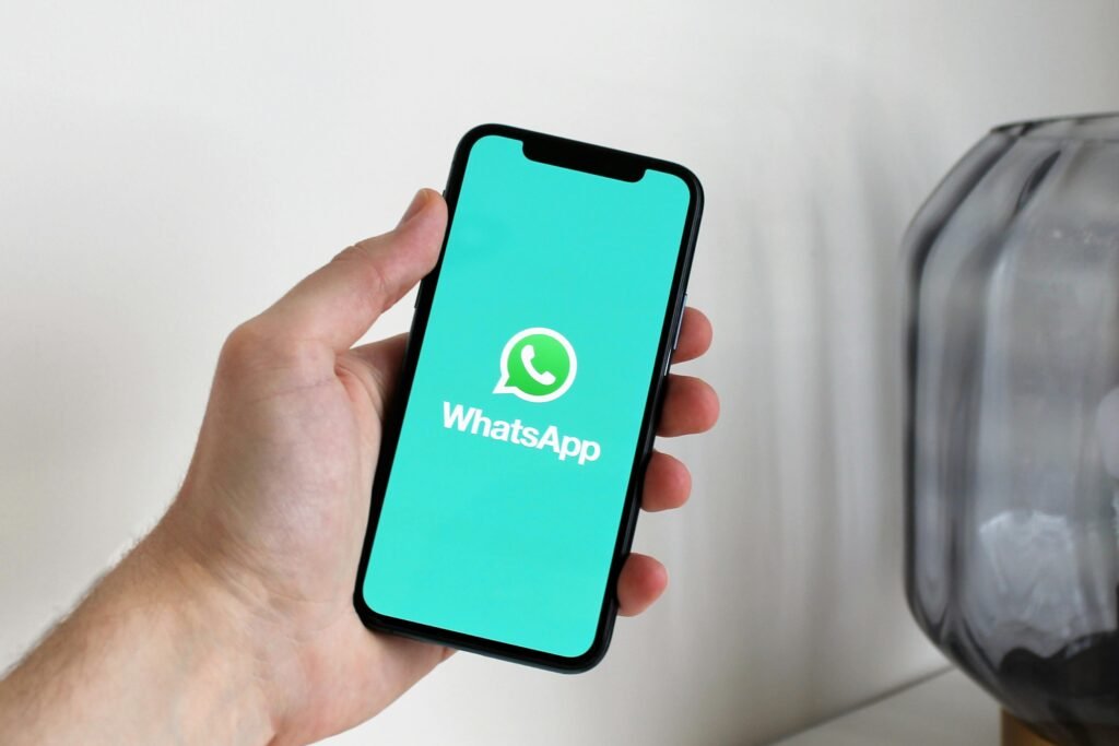 Hand holding a smartphone with WhatsApp open on the screen