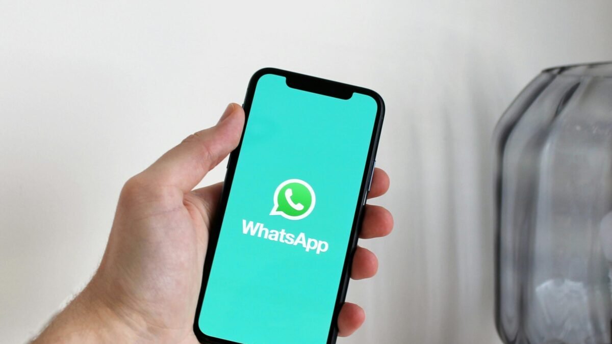 Hand holding a smartphone with WhatsApp open on the screen