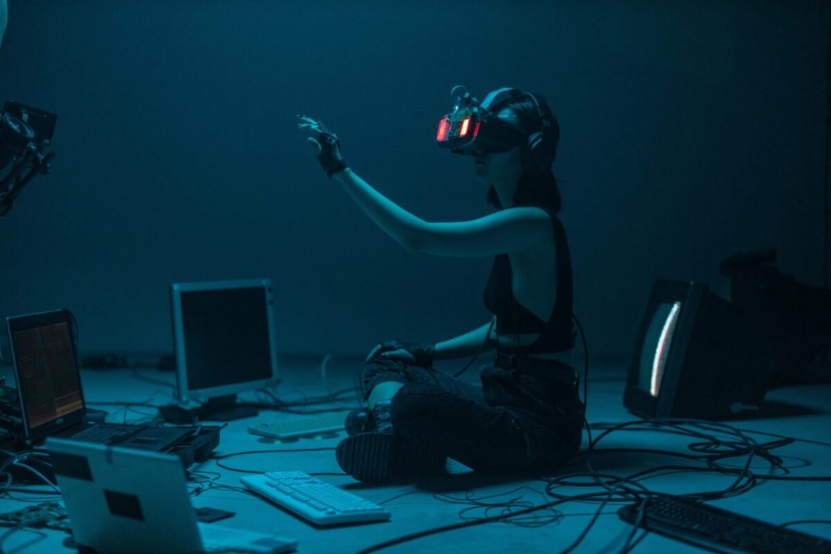 Person using advanced virtual reality headset surrounded by old and modern computer technology, symbolizing the evolution of AI and digital interaction.