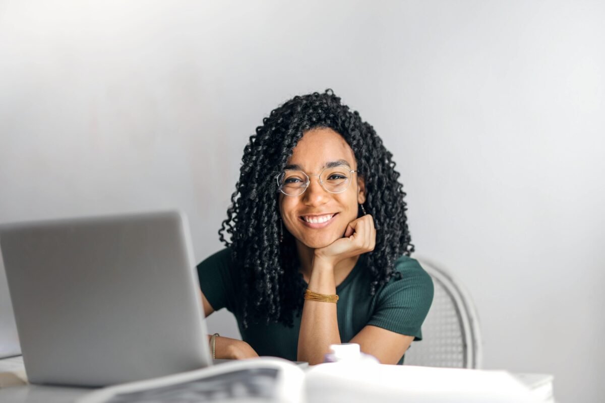 Smiling young woman working on a laptop at home, symbolizing a modern e-commerce entrepreneur in 2025.