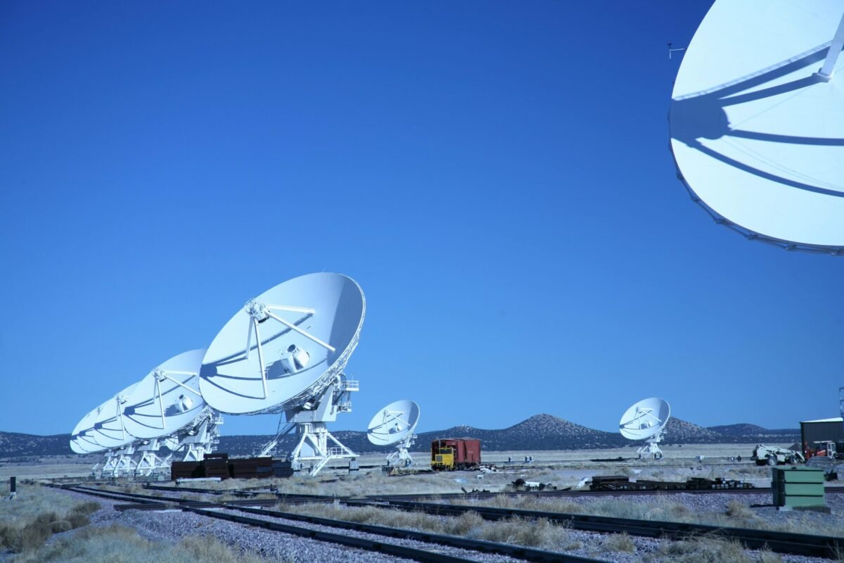 Array of large white satellite dishes under a clear blue sky, representing advanced communication technology.