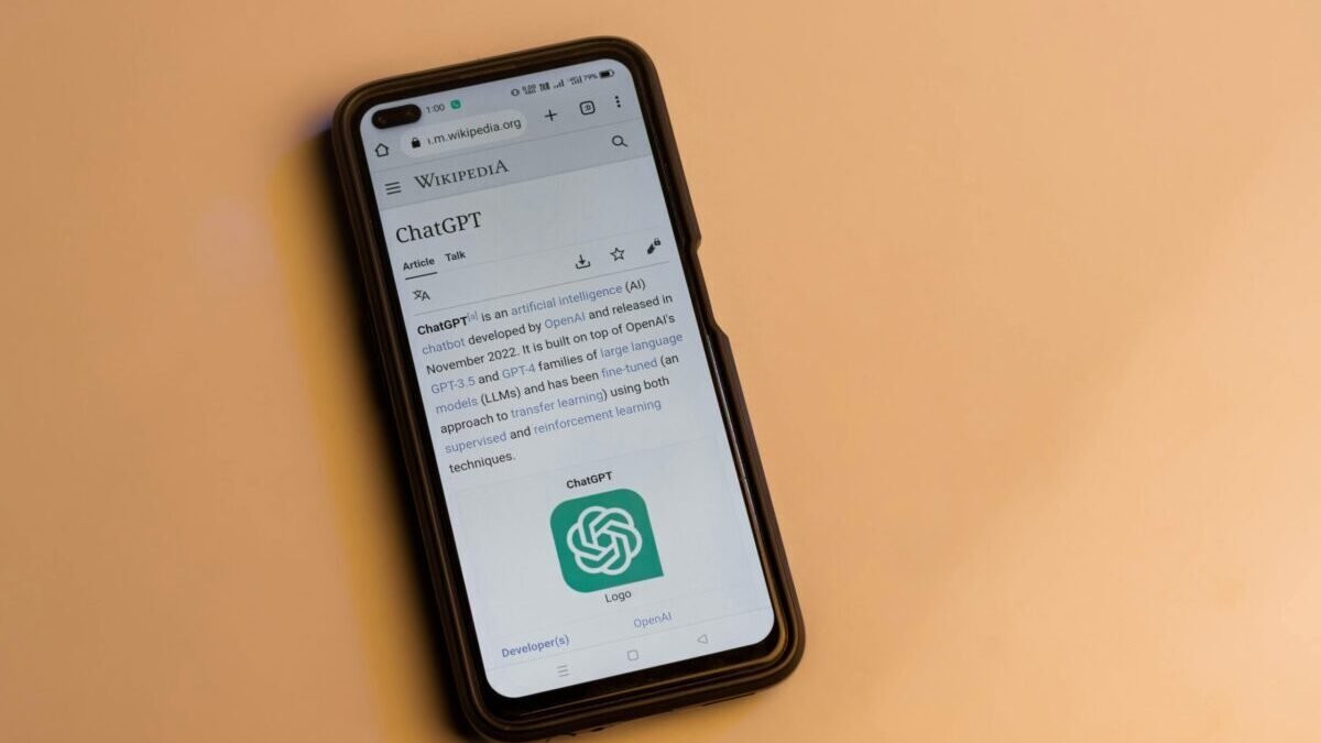 Smartphone displaying the ChatGPT Wikipedia page on a yellow background.