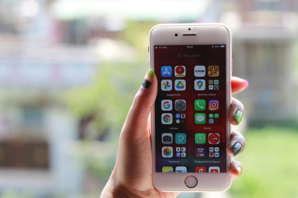 Hand holding a smartphone displaying multiple mobile apps on the home screen