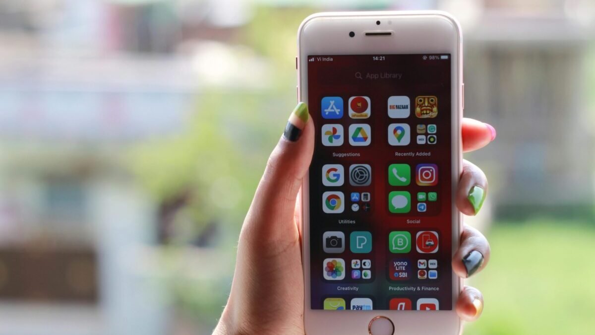 Hand holding a smartphone displaying multiple mobile apps on the home screen