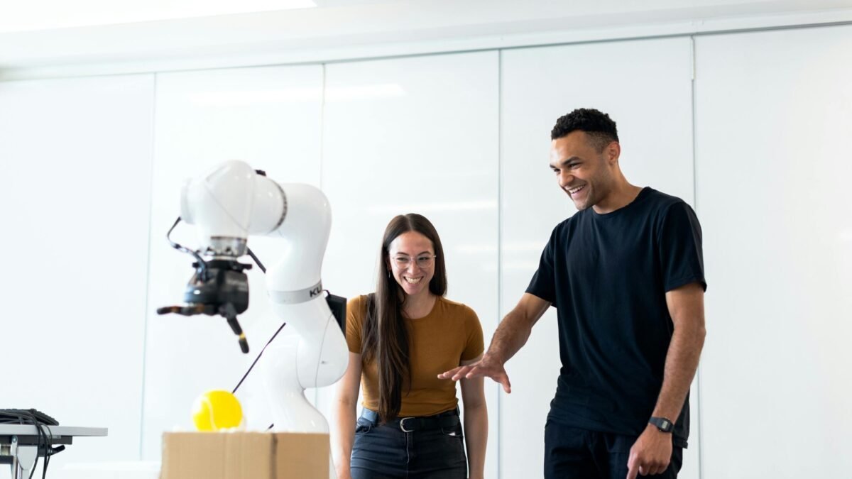 Two people interacting with an AI-powered robotic arm in a tech lab environment