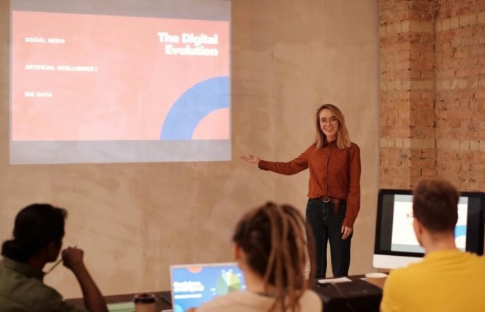 Young woman presenting digital evolution concepts to a classroom audience.