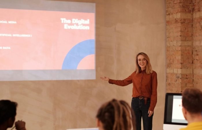 Young woman presenting digital evolution concepts to a classroom audience.