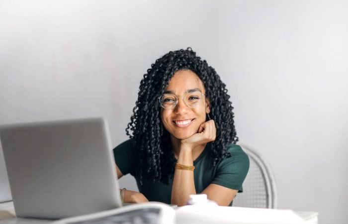 Smiling young woman working on a laptop at home, symbolizing a modern e-commerce entrepreneur in 2025.