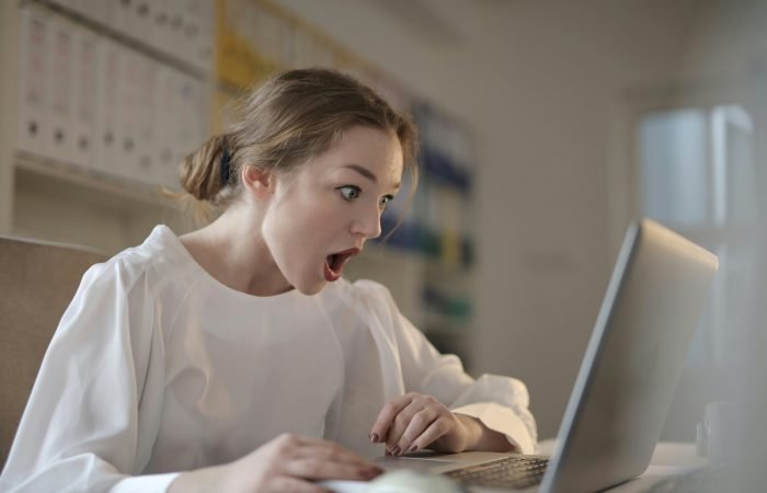 pexels-olly-3784324 Woman shocked while using laptop.