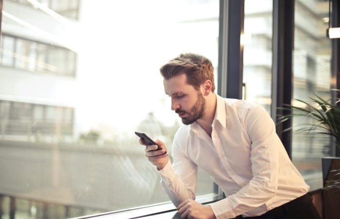 pexels-olly-859265 Businessman checking mobile apps on phone.