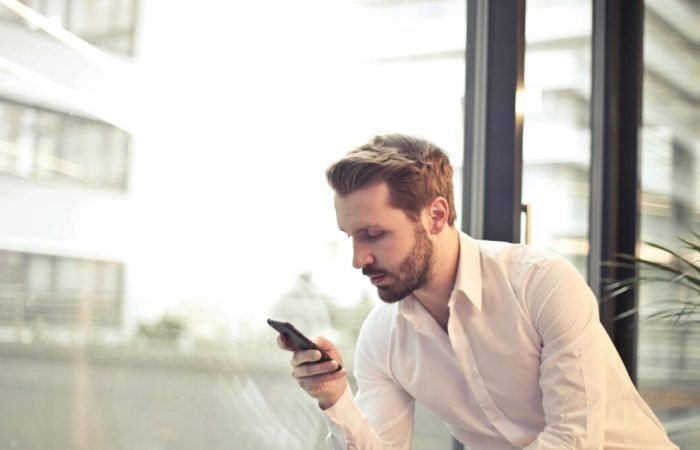 Businessman checking mobile apps on phone.