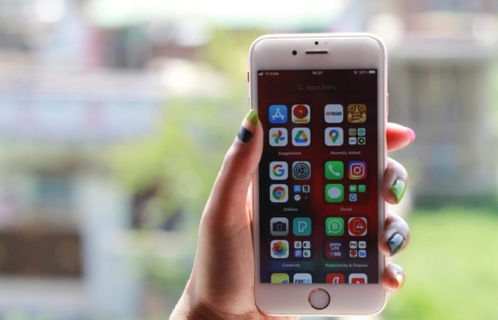 Hand holding a smartphone displaying multiple mobile apps on the home screen