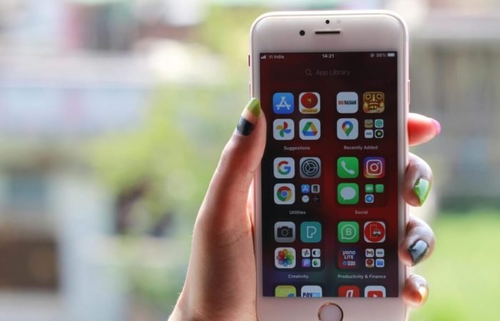 Hand holding a smartphone displaying multiple mobile apps on the home screen