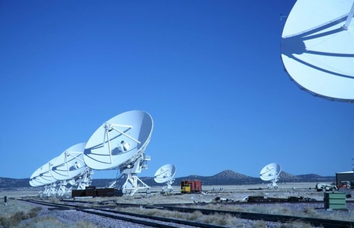 Array of large white satellite dishes under a clear blue sky, representing advanced communication technology.