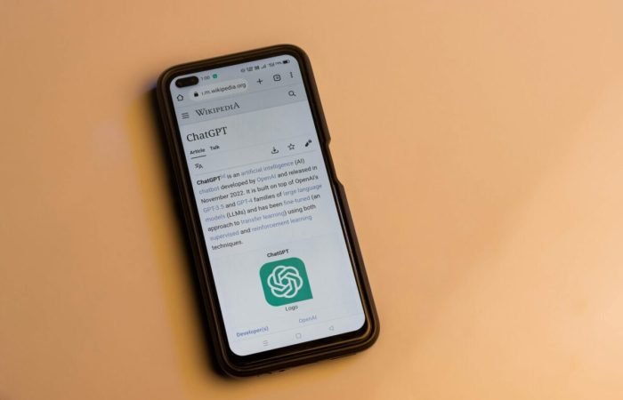 Smartphone displaying the ChatGPT Wikipedia page on a yellow background.
