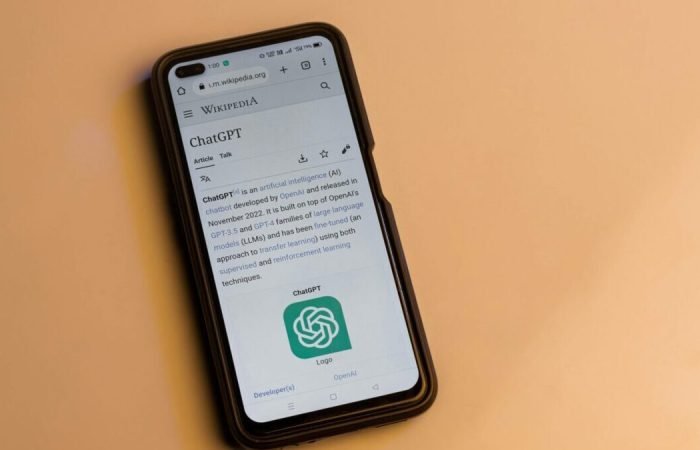 Smartphone displaying the ChatGPT Wikipedia page on a yellow background.