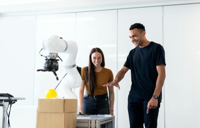 Two people interacting with an AI-powered robotic arm in a tech lab environment