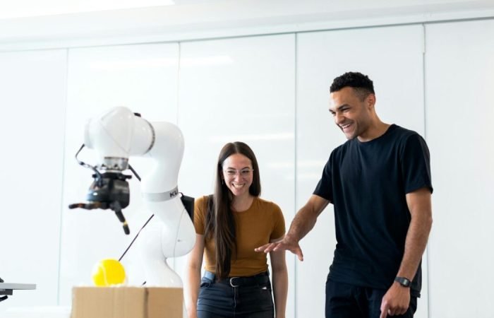 Two people interacting with an AI-powered robotic arm in a tech lab environment