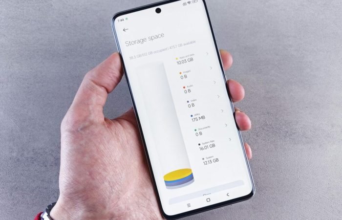 Hand holding a smartphone showing storage space usage on the screen