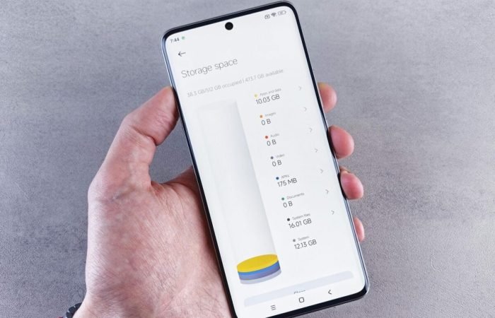 Hand holding a smartphone showing storage space usage on the screen